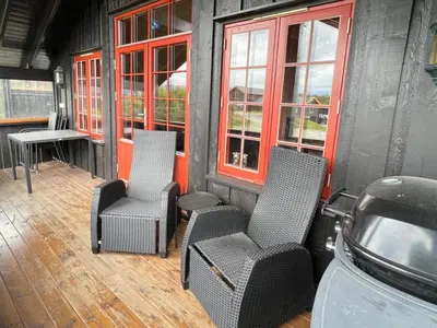 a porch with three chairs and a table and windows at Stadionutsikten in Beitostøl