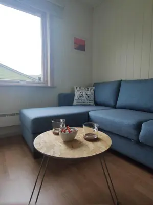 a living room with a blue couch and a table at Guest room in private house in Ålesund