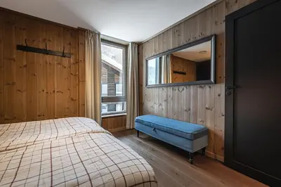 a bedroom with a bed and a blue ottoman and a window at Fyri Tunet Hemsedal in Hemsedal