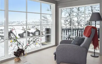a living room with a chair and large windows at Beautiful Home In Rauland With Sauna in Rauland