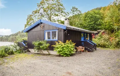 a black cabin with a table and chairs in front of it at 3 Bedroom Awesome Home In Vikersund in Vikersund