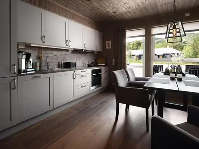 a kitchen with white cabinets and a table with chairs at Flott leilighet i Vestlia - ski in/ski out in Geilo
