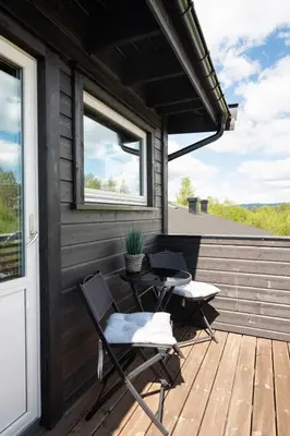 a patio with two chairs and a table on a deck at Flott leilighet i Vestlia - ski in/ski out in Geilo