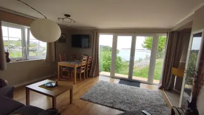 a living room with a table and chairs and windows at Apartment , Øygarden, Bergen in Torsteinsvik