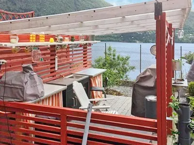 a deck with a table and a grill on the water at 8 person holiday home in Bruvik-By Traum in Bruvik