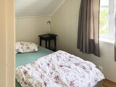 a bedroom with a bed and a table and a window at 6 person holiday home in Hernar-By Traum in Bøvågen
