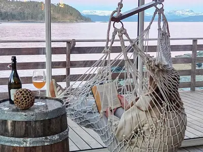 a hammock on a deck with a glass of wine at 6 person holiday home in Tansøy-By Traum in Tansøy