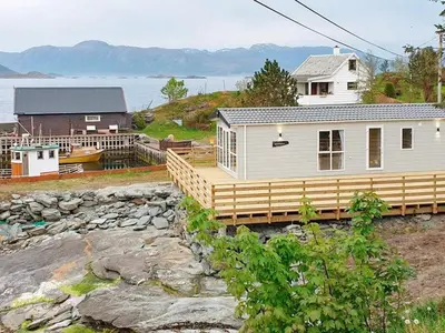 a white house with a deck next to the water at 6 person holiday home in Tansøy-By Traum in Tansøy
