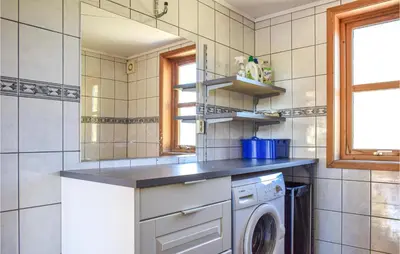 a kitchen with a washing machine and a sink at Nice Home In Os With House Sea View in Oma