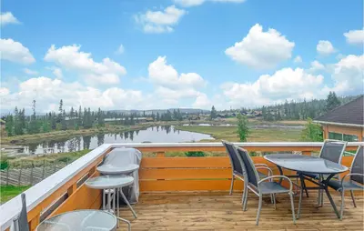 a balcony with chairs and tables and a view of a river at Stunning Apartment In Lillehammer in Lillehammer