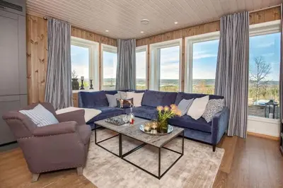 a living room with a blue couch and chairs and windows at Flott fritidsleilighet i Bualie på Golsfjellet in Gol