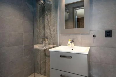 a bathroom with a sink and a shower with a mirror at Riddertunet apartment 101 in Beitostøl