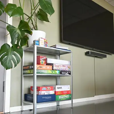 a book shelf filled with books next to a tv at Rumi Hostel in Trondheim