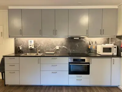 a kitchen with white cabinets and a sink and a microwave at Brekke Apartments in Flåm