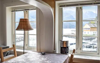 a dining room with windows and a table with a lamp at 2 Bedroom Cozy Home In Vallavik in Kaland