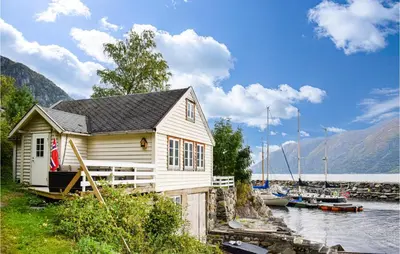 a small house next to a body of water with boats at 2 Bedroom Cozy Home In Vallavik in Kaland