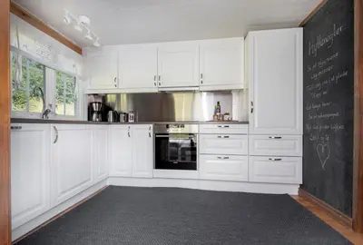 a kitchen with white cabinets and a chalkboard on the wall at Økslevegen 2 in Stranda