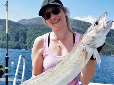 a woman holding a fish on a boat at 7 person holiday home in Huglo-By Traum in Nordhuglo