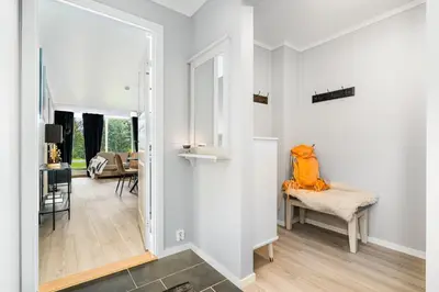 a white hallway with a chair and a mirror at Leilighet Beitostølen sentrum, terrasse og innendørs parkering in Beitostøl