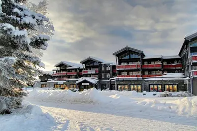 a large building in the snow with snow covered grounds at Leilighet Beitostølen sentrum, terrasse og innendørs parkering in Beitostøl