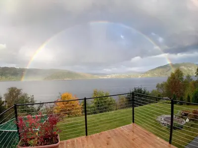 a rainbow over the water with a balcony with a view at Bergen Sunrise Terrace Apartment in Bergen