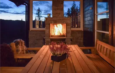 a fireplace on a screened porch with a wooden table at Lovely Home In Hjartdal With Sauna in Hjartdal