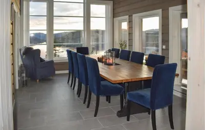 a dining room with a wooden table and blue chairs at Lovely Home In Hjartdal With Sauna in Hjartdal