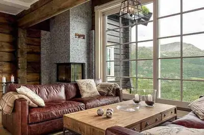 a living room with a leather couch and a table at Stor og eksklusiv tømmerhytte Hemsedal in Grøndalen