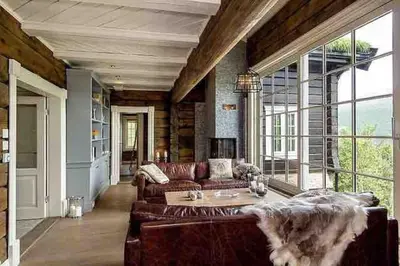 a living room with a leather couch and large windows at Stor og eksklusiv tømmerhytte Hemsedal in Grøndalen