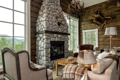 a living room with a stone fireplace in a house at Stor og eksklusiv tømmerhytte Hemsedal in Grøndalen