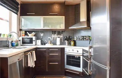 a kitchen with wooden cabinets and a stainless steel refrigerator at Cozy Home In Norheimsund With Sauna in Norheimsund