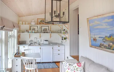 a kitchen with white cabinets and a table in a room at 1 Bedroom Nice Home In Skånevik in Skånevik