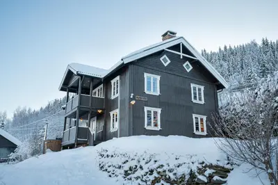 a black house with snow on the ground at Stamp and sauna! Small farm with fantastic view! in Favang