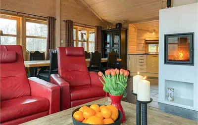 a living room with red chairs and a table with a candle at Cozy Home In Straumgjerde With Sauna in Brunstad