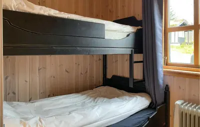 a bunk bed in a wooden room with a window at Cozy Home In Straumgjerde With Sauna in Brunstad