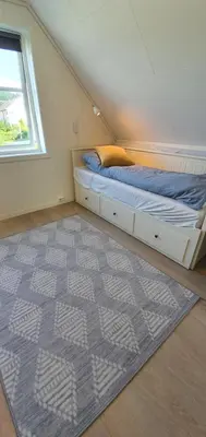 a bedroom with a bed and a window and a rug at The Fjord House in Snofugl