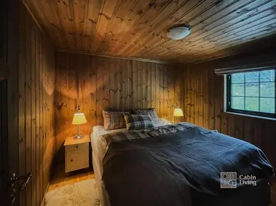 a bedroom with a bed and a wooden wall at Large cabin at Nesfjellet with lovely view, inddor Jacuzzi & sauna in Nes i Ådal