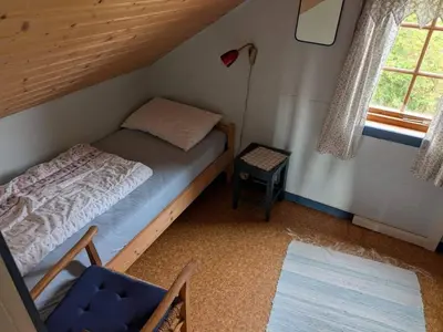 a small bedroom with a bed and a blue chair at 4 person holiday home in HARDBAKKE-By Traum in Hardbakke