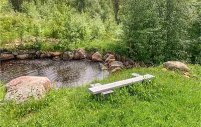 a bench sitting in the grass next to a pond at 5 Bedroom Gorgeous Home In Eggedal in Eggedal