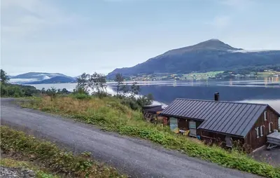 a house on the side of a road next to a lake at Stunning Home In Gjemnes With Wifi in Stokke