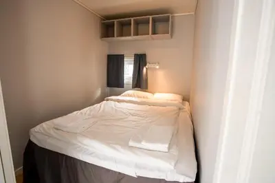 a small bedroom with a bed with white sheets at Koie Standard in Stranda