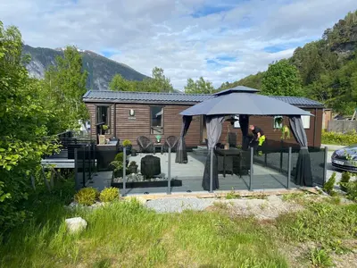 a patio with an umbrella in front of a cabin at Koie Holiday Home 3 in Stranda