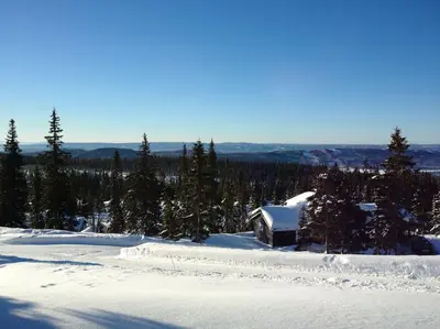 a cabin in the snow with trees in the background at Stor familiehytte på Småsætra, Sjusjøen in Sjusjøen