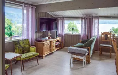 a living room with a couch and a tv and windows at 4 Bedroom Nice Home In Vikersund in Vikersund