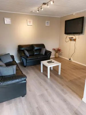 a living room with a black leather couch and a table at peaceful place in Hønefoss