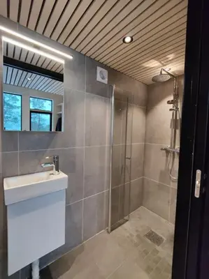 a bathroom with a shower and a sink and a mirror at Minihuset ved skogen in Isfjorden
