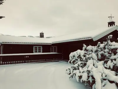 a barn covered in snow with a snow covered tree at Vestlia Ski in Geilo