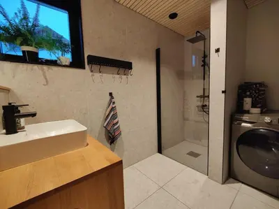 a bathroom with a sink and a shower and a television at Huset ved skogen in Isfjorden