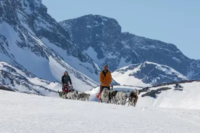 two people and a group of dogs in the snow at Skåbu Fjellhotell in Skåbu