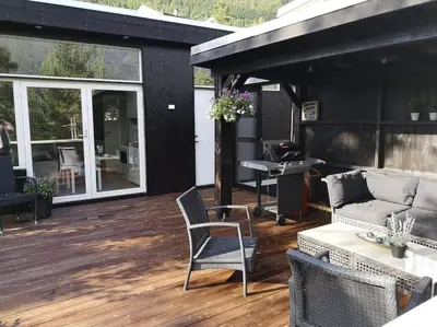 a patio with a couch and chairs on a deck at Gjestehus i Sogndal med utsikt over fjord og fjell in Sogndal